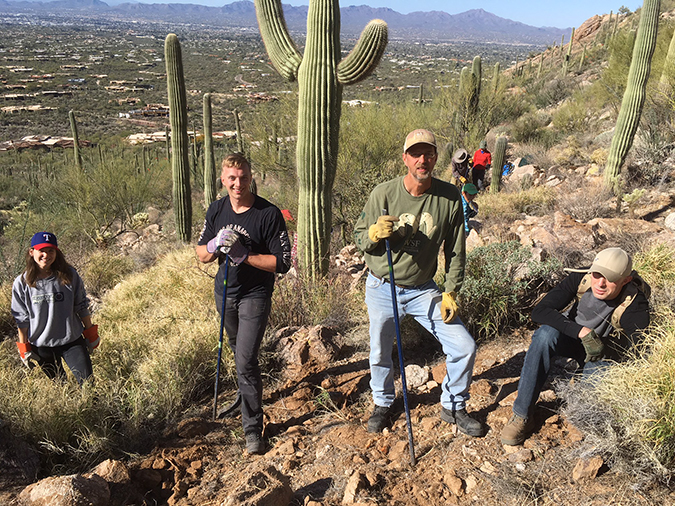 Group of volunteer buffelgrass diggers pausing to pose in the field with tools